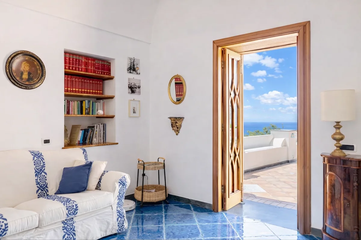Soggiorno Villa Antonella Praiano libreria divano maiolica blu accesso terrazza